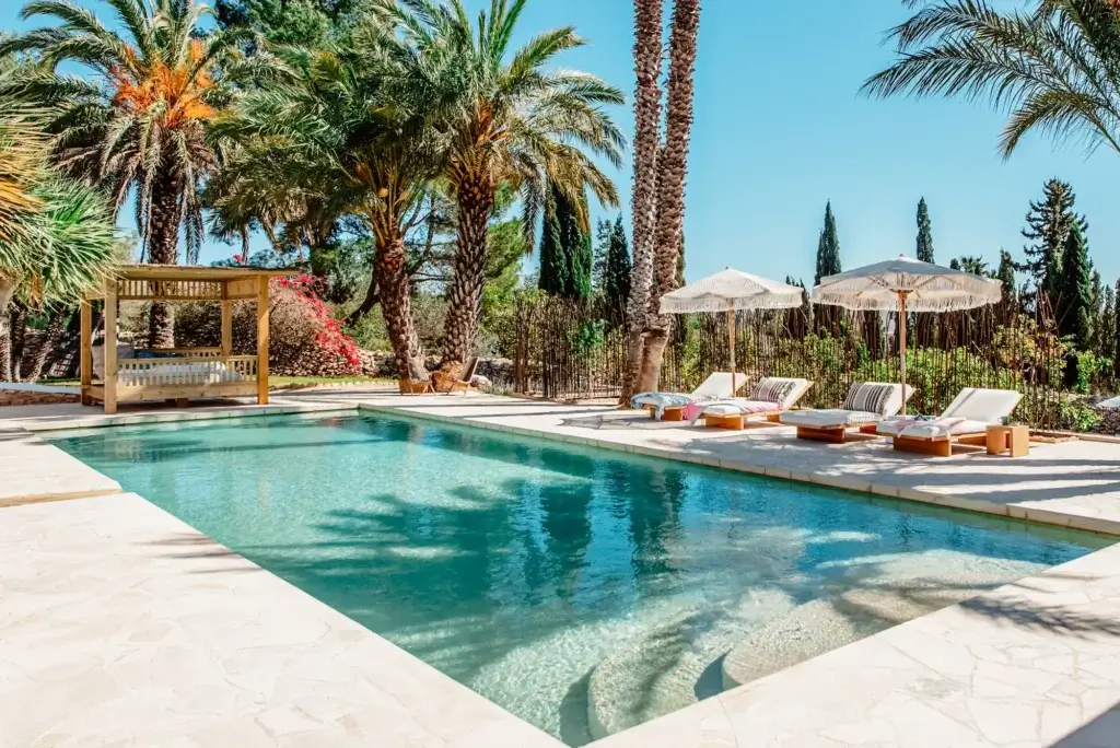 Swimming pool at Can Sabina Villa, Ibiza, with sun loungers, parasols, and a shaded garden cabana.