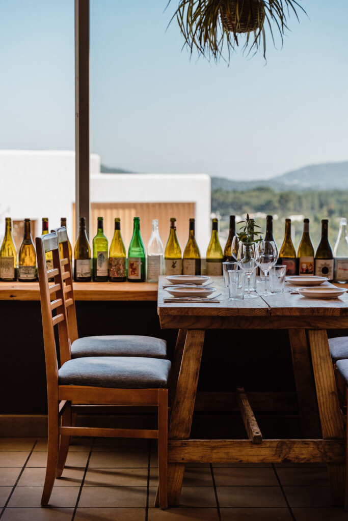 Outdoor dining table set with wine glasses and bottles at Casa Lhasa, Finca Delica in San Lorenzo, Ibiza.