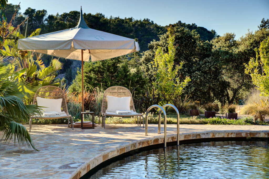 Rattan chairs beneath a parasol beside the pool at Fincadelica villa, Ibiza
