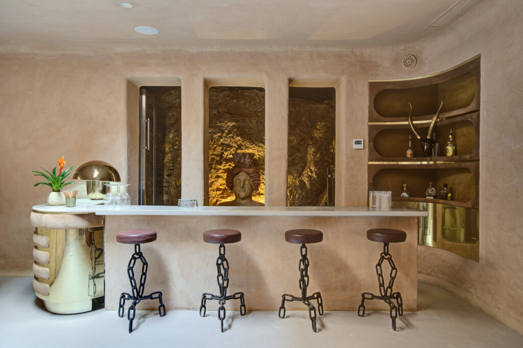 Cave Bar at Finca Delica in San Lorenzo, Ibiza, with a pale stone counter, sculpted bar stools and a rock alcove.