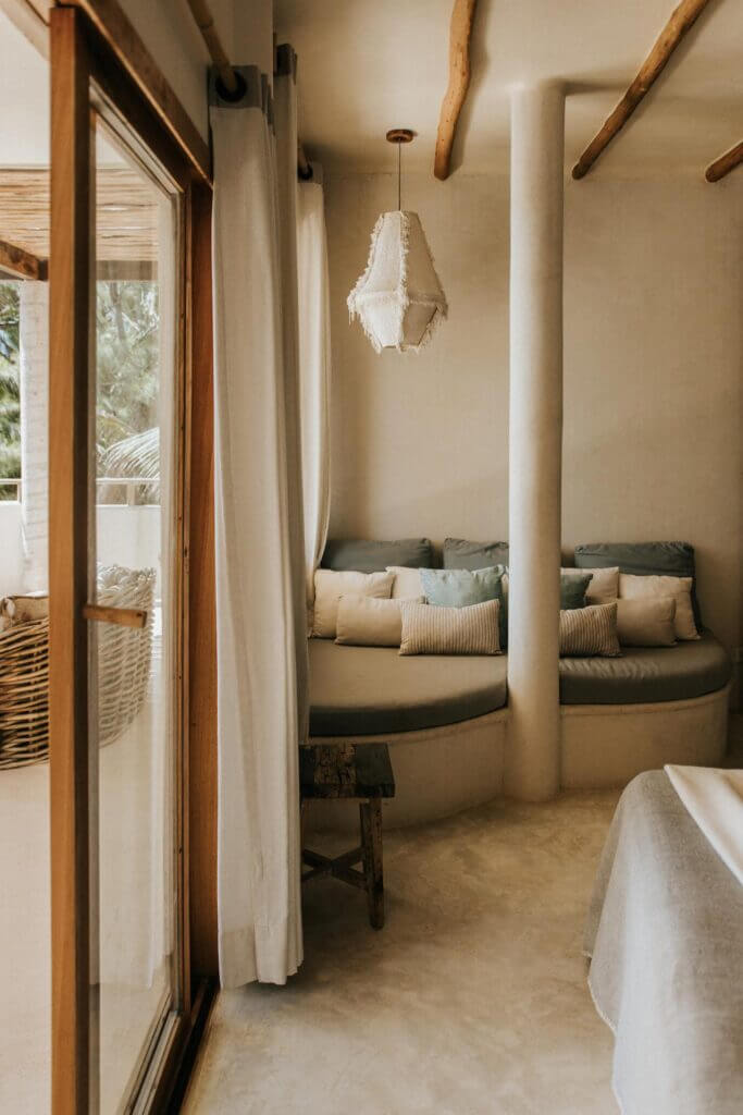 Built-in cushioned sitting nook beside a bedroom’s glass doors and bed.