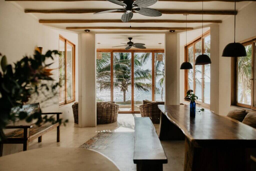 Open-plan dining area with wood tables and a view through glass doors to the palms.