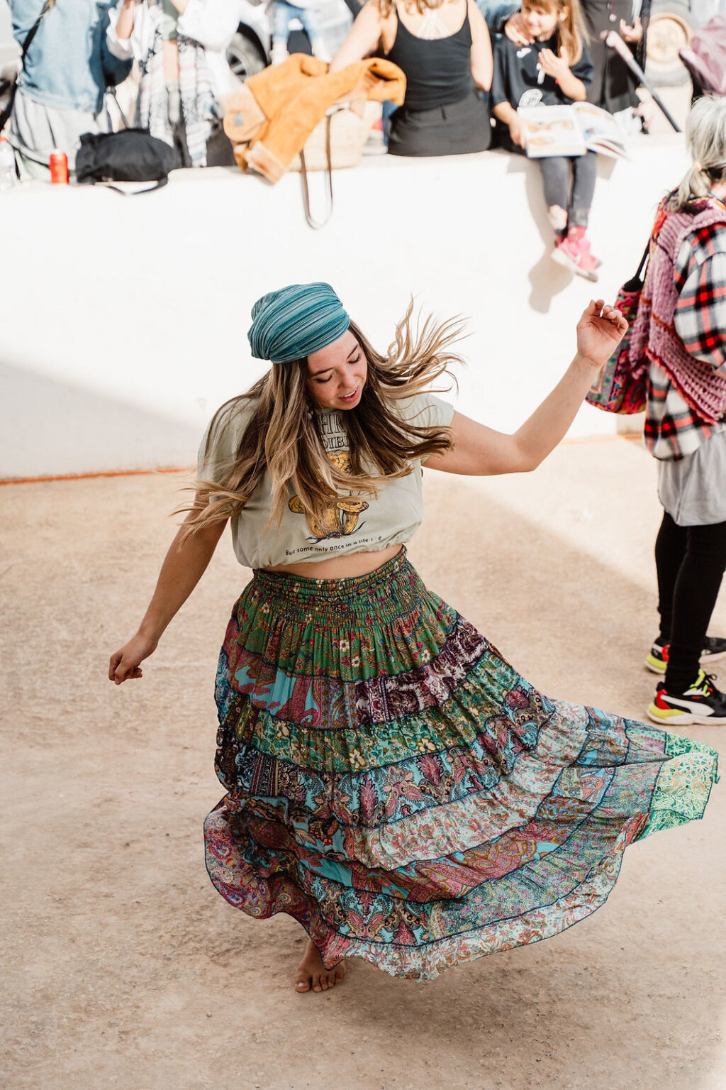 Woman in a flowing patterned skirt dancing at Sant Jordi Flea Market, Ibiza.